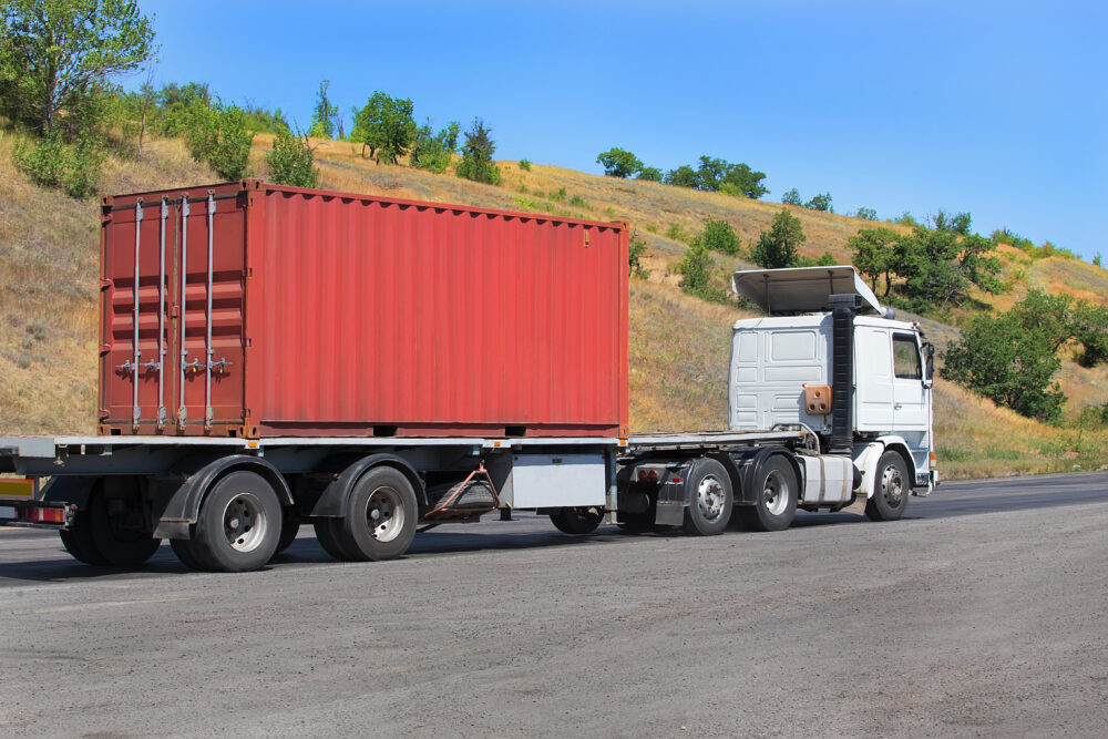 trailer transports container on highway in country